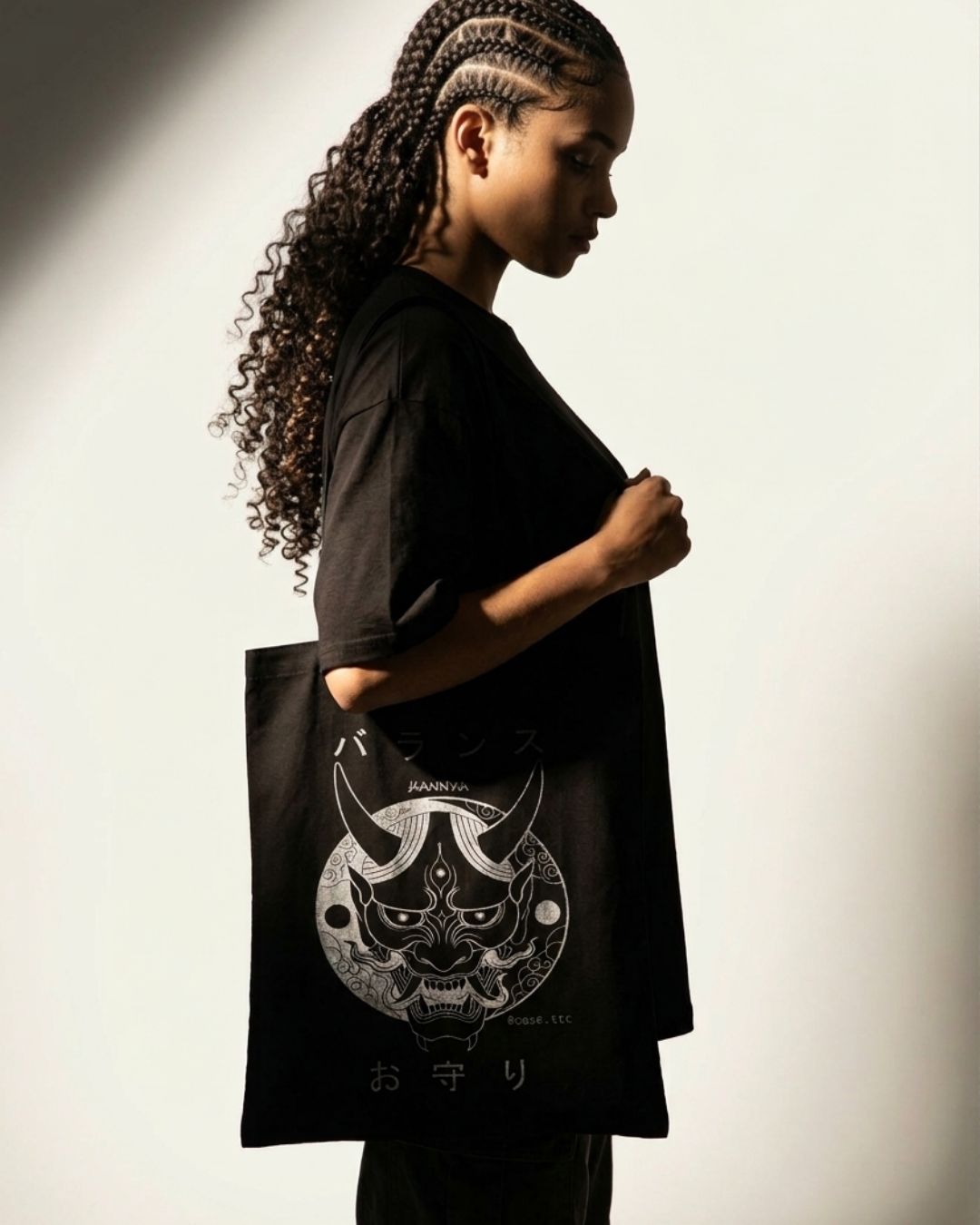 Tote Bag Hannya — bolsa de lona preta com estampa da máscara Hannya, modelo carregando